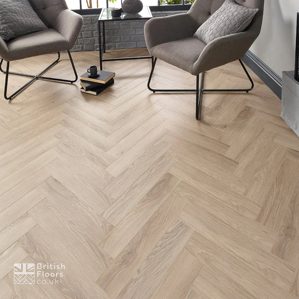 Wooden floor with herringbone pattern in a room with chairs and a coffee table.